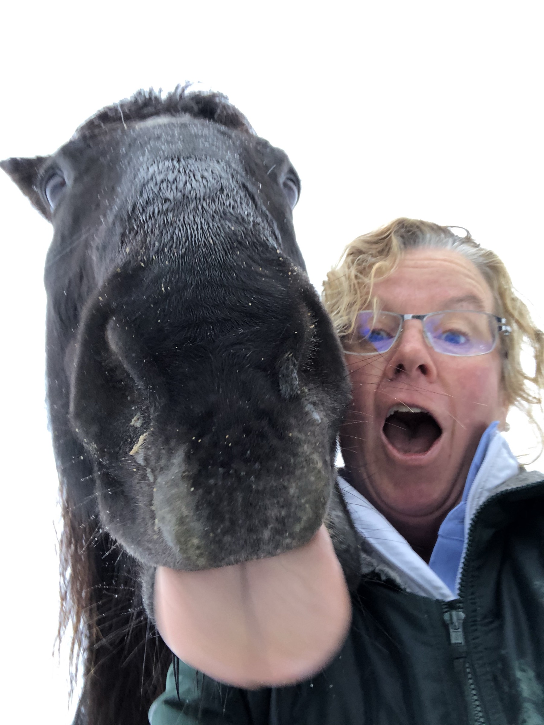 Mary McEachern with her horse Vesper, mid-nuzzle, on a snowy morning.